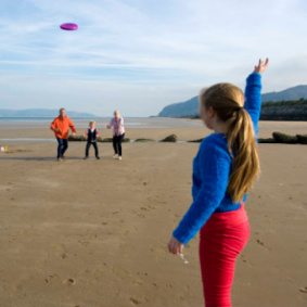 Image of family playing frisbee on Penmaenmawr beach